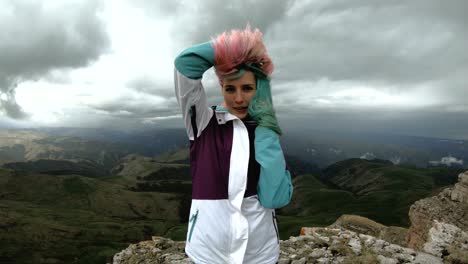 girl young woman dances on the edge of a cliff of a plateau having fun nature mountains flowers beautiful attractive playing cheerful satisfied joy leisure funny laughing smile looking camera wonderful landscape summer happy weekend