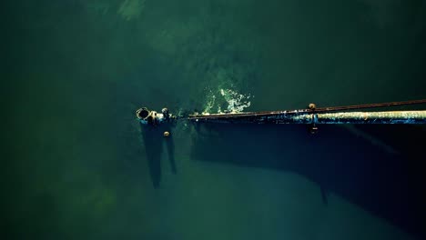 Aerial-top-down-shot-of-rusty-leaking-pipe-running-into-lake-surrounded-by-mangroves,-dumping-sewage