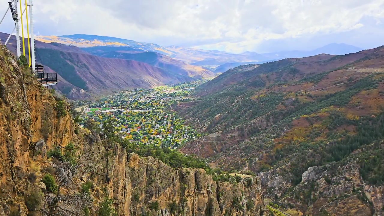 Panorama autunnale da un punto panoramico elevato sopra Glenwood Springs, Colorado, che mostra il fiume Colorado, quartieri colorati, alberi sempreverdi e aspre montagne del canyon sotto un cielo luminoso