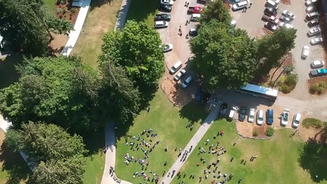 aerial birds eye view over lush green summer camp entrance where campers await parents to arrive to take them home while others are registering to start the new week of fun outdoor fitness adventure