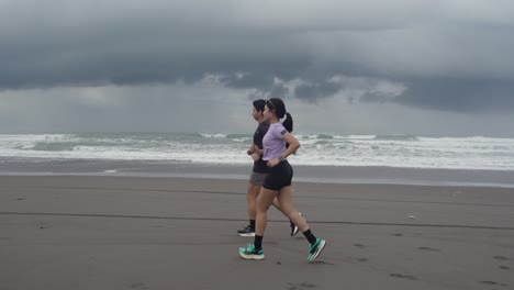 couple running on a beach in cloudy weather