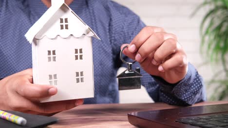 man holding model house and key