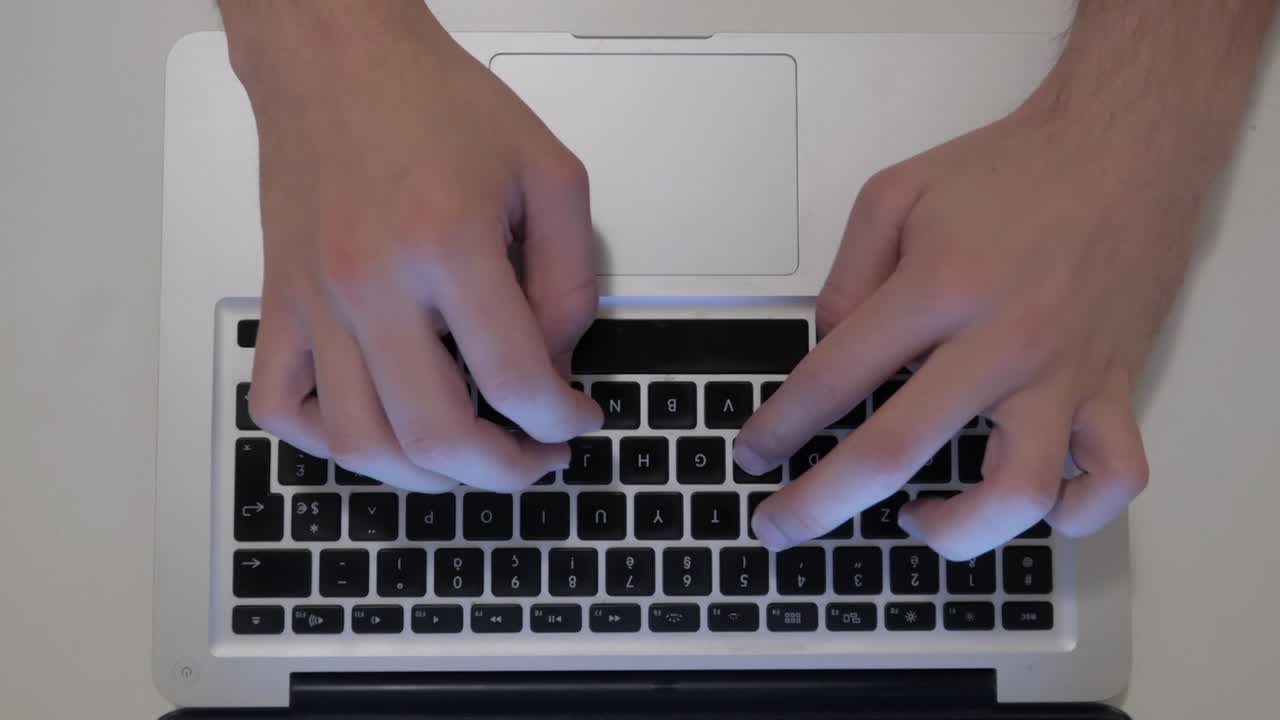 vista superior de manos masculinas escribiendo en el teclado de la computadora portátil