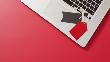 vista aérea de una computadora portátil con etiquetas de venta negras y rojas sobre fondo rojo