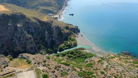 Weaving-shot-of-river-coming-from-canyon,-going-into-aqua-ocean,-Crete