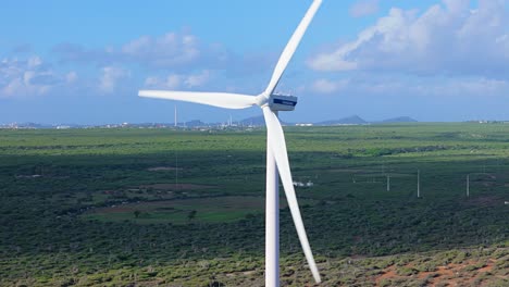 Drone-orbit-around-wind-turbine-mill-with-long-blades-spinning-with-cloud-shadow-behind