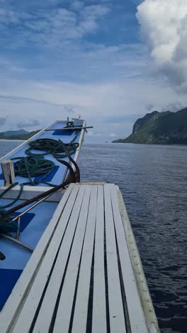 vertical video, traditional bangka filipino boat sailing between islands in el nido archipelago, philippines