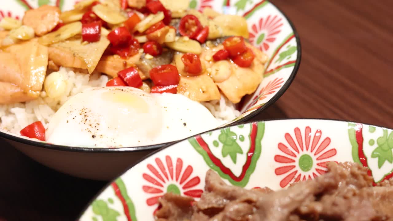 Camera smoothly pans across vibrant Thai rice dishes, highlighting colorful toppings, fried egg, and stir-fried beef under bright, even lighting on a wooden table