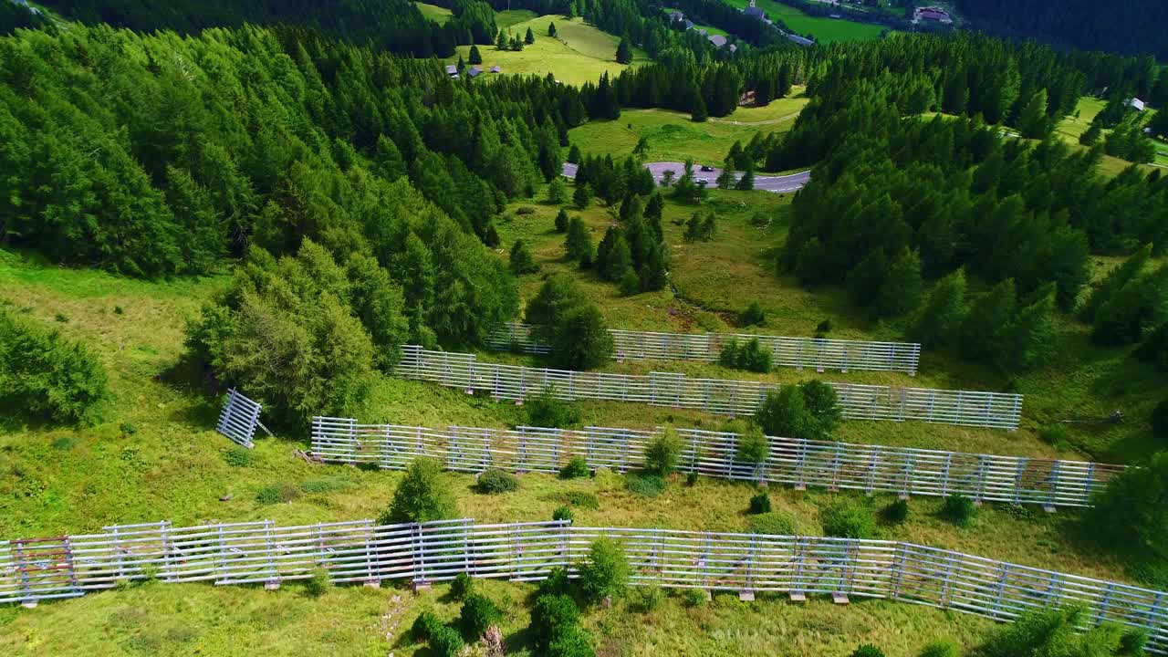 Drone shot of alpine snow fences in green summer landscape, Austria mountain