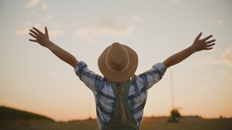 Woman farmer enjoying sunset in field