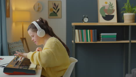 girl with down syndrome putting on headphones and playing synth
