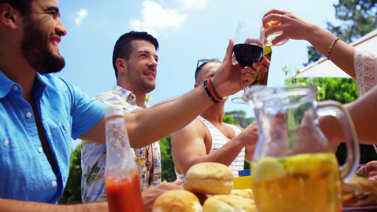 grupo de amigos felices brindando botellas de cerveza y vasos en una fiesta de barbacoa al aire libre
