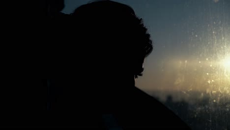 closeup-girl-fixes-long-curly-hair-near-window-at-sunset