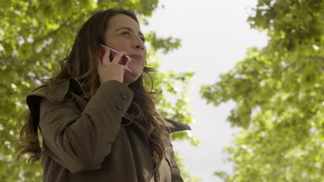 smiling young woman talking on smartphone in park.