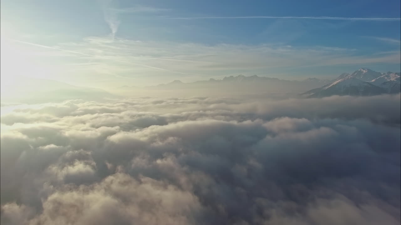 Sun shinning above cloudscape and mountain range, aerial drone view