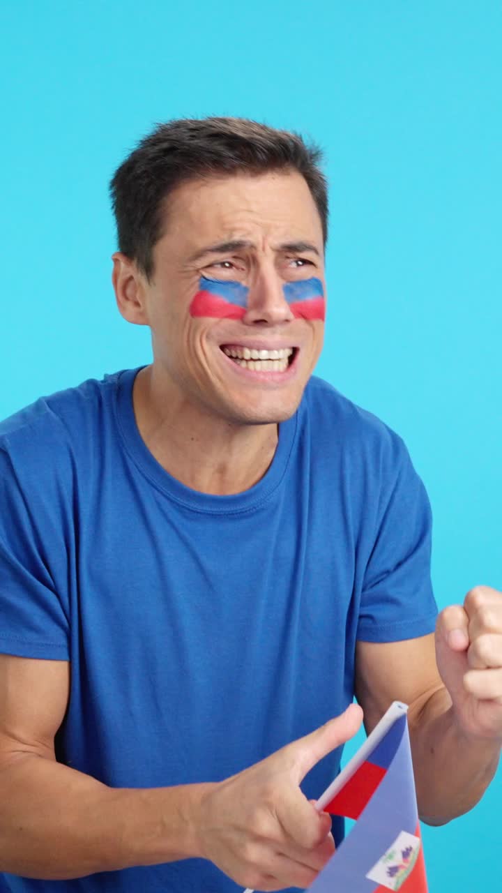 Nervous man cheering for Haiti during a match looking away