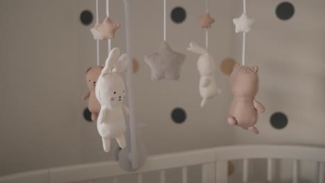 cute stuffed baby animals rotating above white wooden crib in nursery