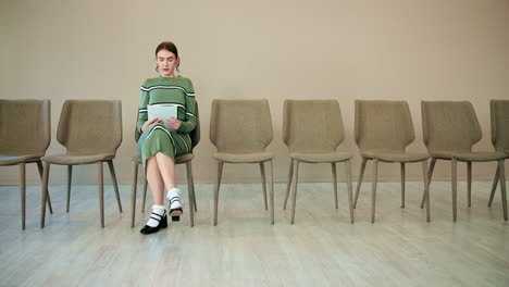 mujer sentada en una sala de espera para una entrevista de trabajo