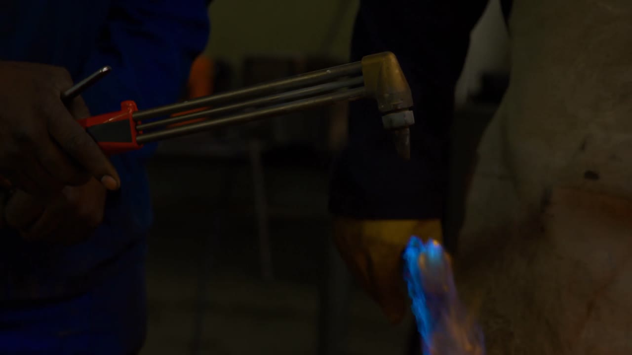 Metalsmith lighting welding torch in workshop 4k