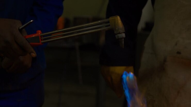 Metalsmith lighting welding torch in workshop 4k