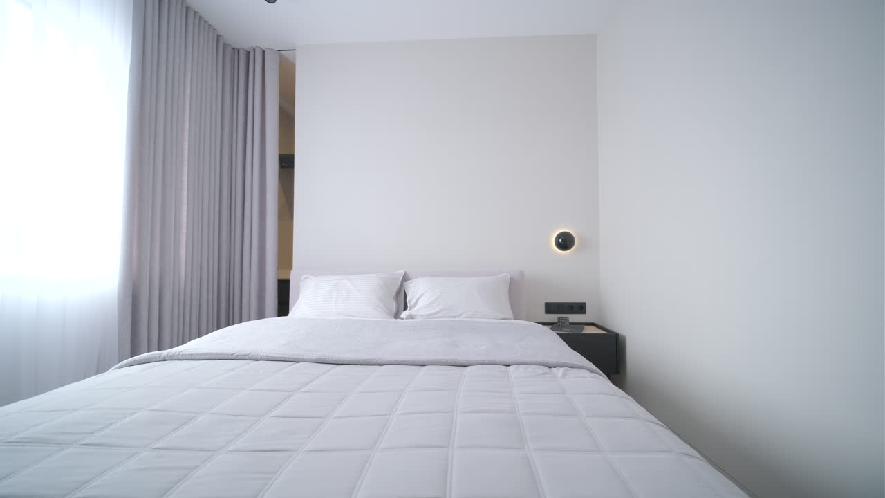Camera da letto moderna e minimalista con letto bianco e tende.