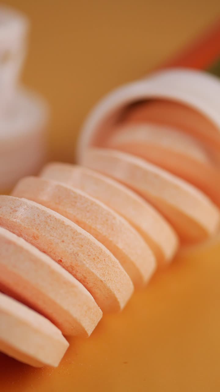 Primo piano di compresse effervescenti di vitamina C arancioni che fuoriescono dal contenitore