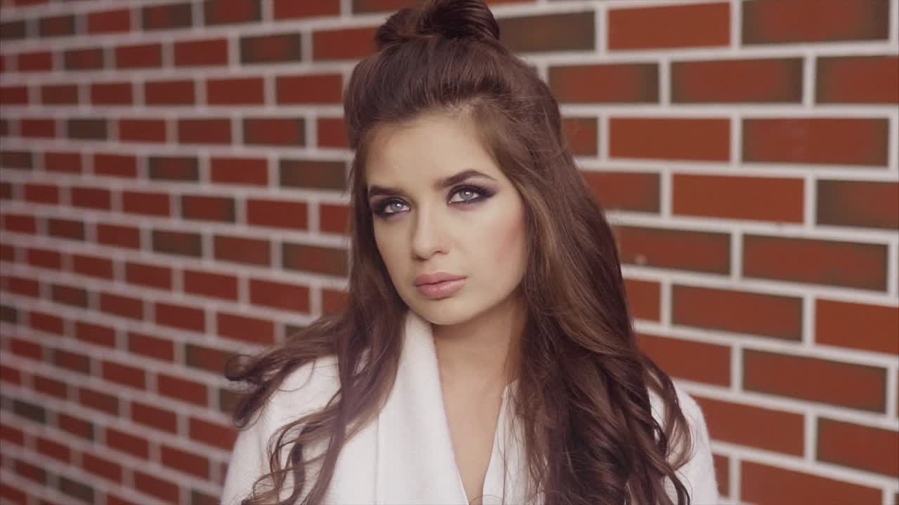 hermosa mujer con un peinado elegante frente a una pared de ladrillo