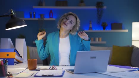 женщина, работающая в домашнем офисе, зевает и расслабляется перед камерой.