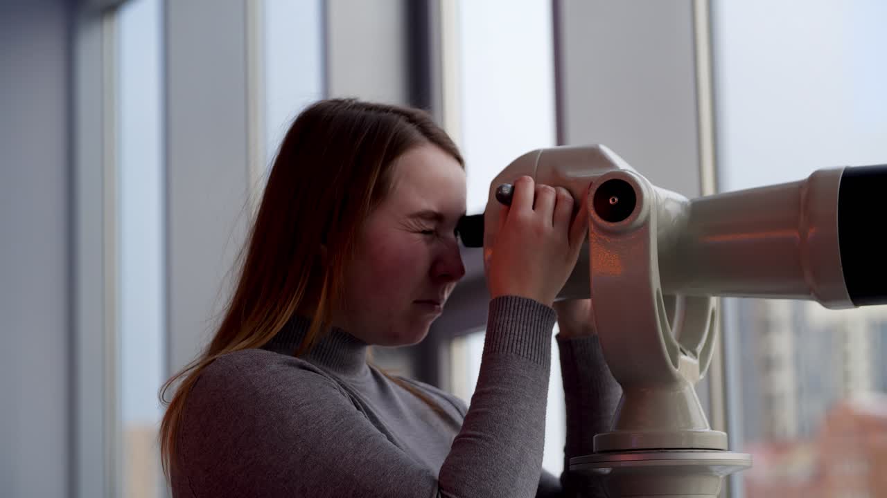 Woman looking through a large telescope
