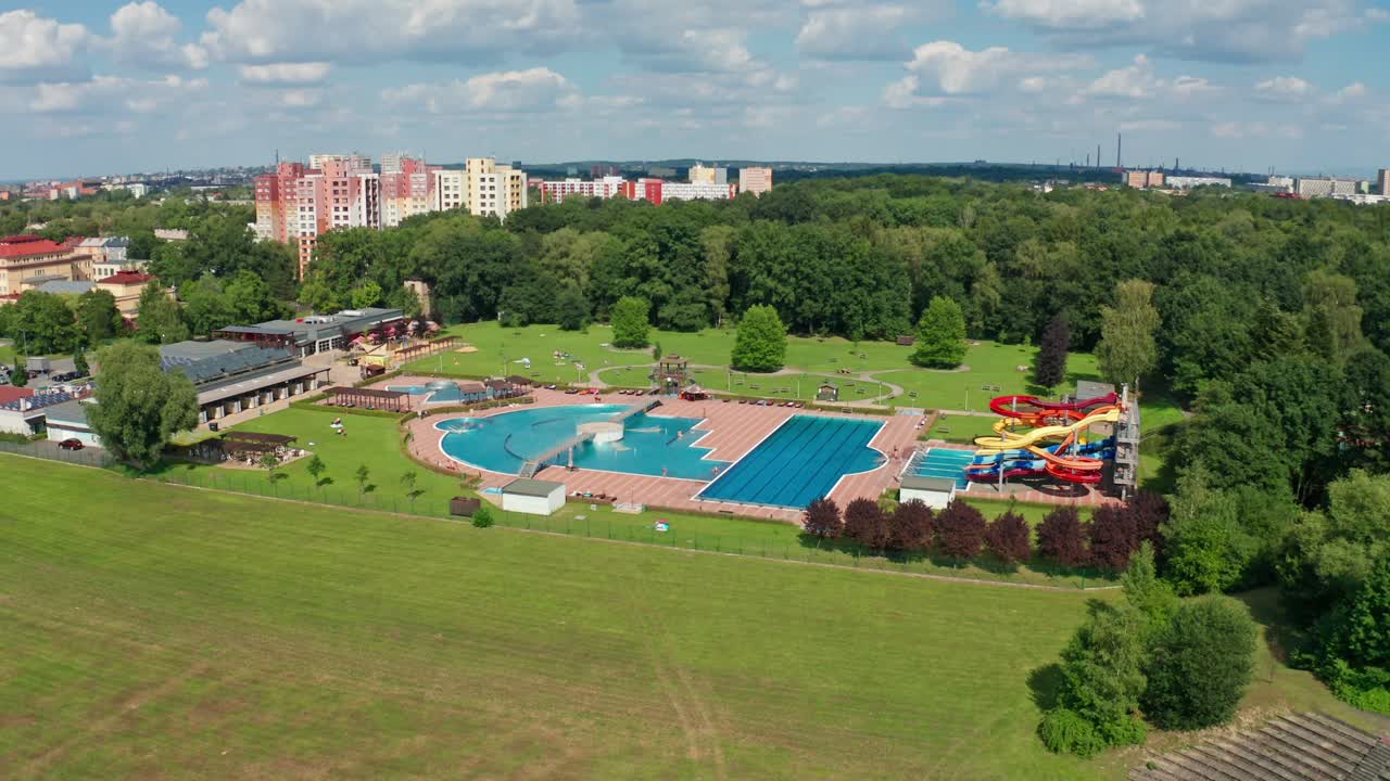 fotografía aérea de un parque acuático en el centro de la ciudad con piscinas y toboganes de agua durante el verano