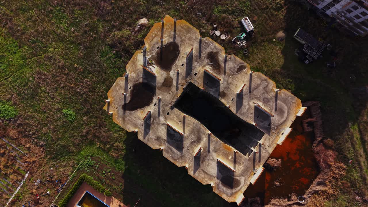 Aerial view of an abandoned structure with shadows and overgrowth