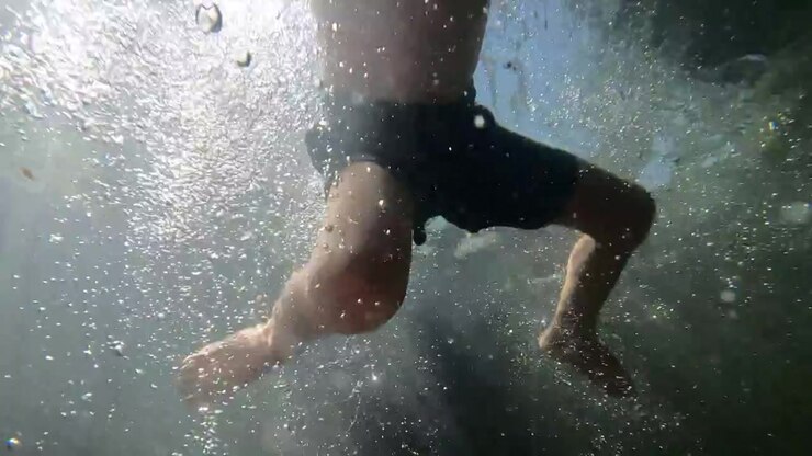 Slow Motion Footage of Child Swimming Through Water with Bubbles