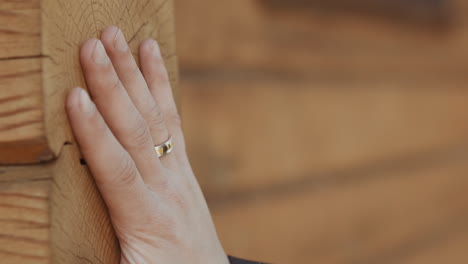 gentleman with wedding ring touches natural log wall