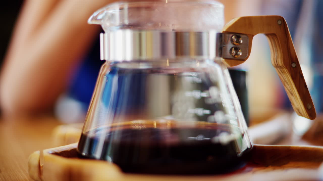 Close up of a glass coffee pot standing on a wooden tray