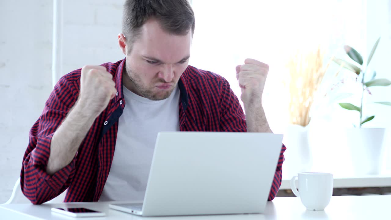 joven enojado gritando mientras trabajaba en la oficina