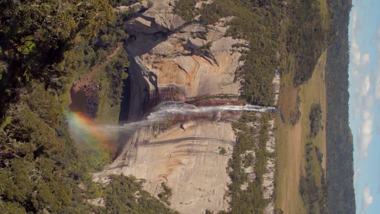 parque nacional chapada dos guimarães, mato grosso, brasil - una vista impresionante de las aguas en cascada en cachoeira véu da noiva, mejorada por arco iris brillantes - toma vertical