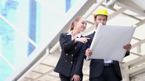 engineer and business woman holding blueprint with talking discuss project together. concept of project management, business meeting, strategy and engineering.