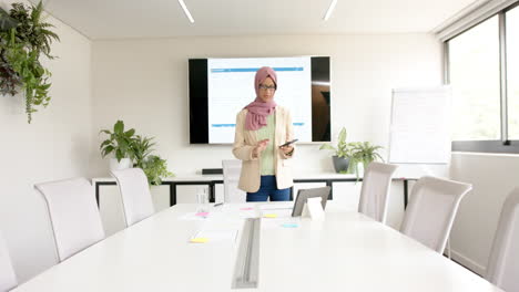 Mujer-De-Negocios-Casual-Birracial-En-Hijab-Hablando-Por-Teléfono-Inteligente-En-La-Sala-De-Reuniones,-Cámara-Lenta