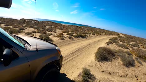 suv drives quickly down bumpy sandy desert road