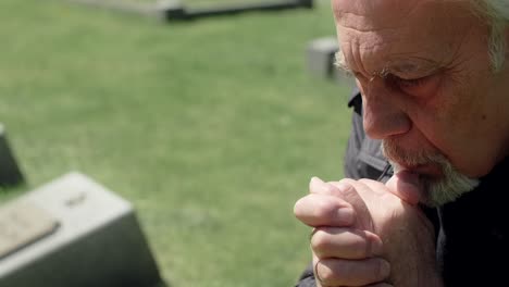 elderly man praying in a cemetery