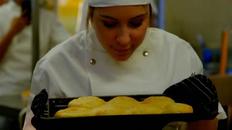 chef femenino oliendo bandeja de galletas en la cocina 4k