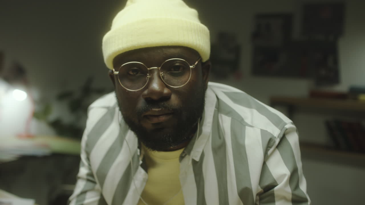 Close-up portrait of a man wearing a yellow beanie and glasses