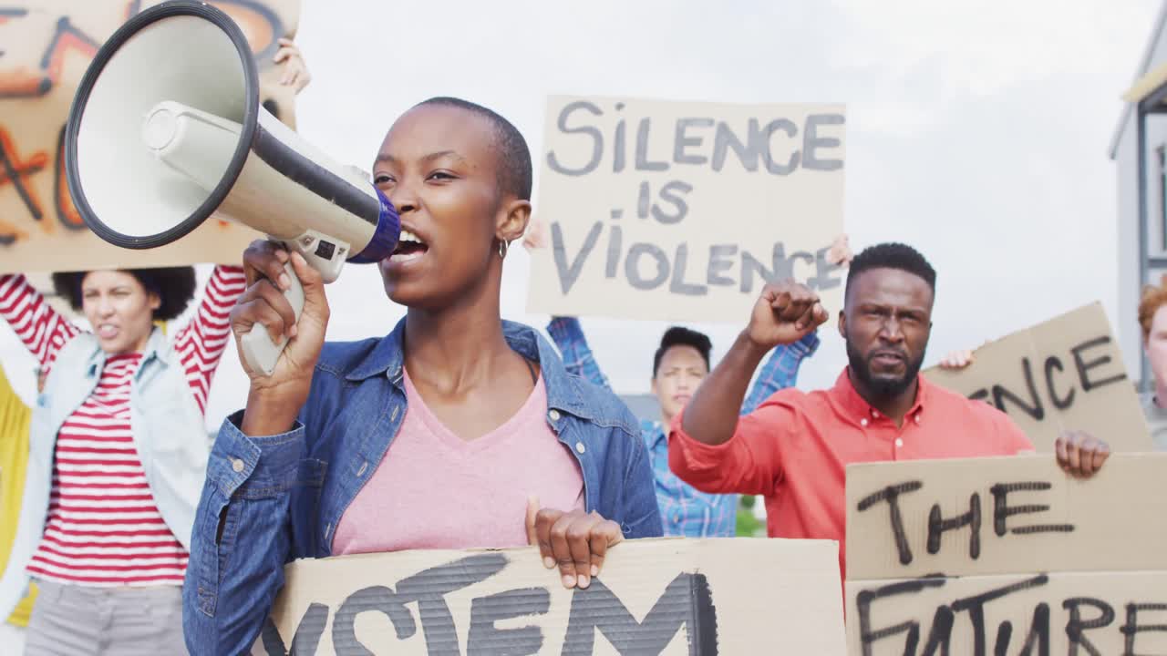 un gruppo eterogeneo di manifestanti con striscioni di cartone e urlando