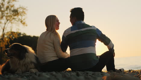 young couple and dog on beach at sunset