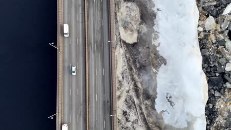 Un-Puente-Con-Autos-Y-Una-Carretera-Con-Una-Línea-Blanca,-Un-Río-Con-Hielo-A-La-Derecha