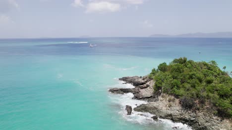 Serene-aerial-wide-shot-of-water-crashing-on-two-archipelago-rocks-and-the-beach-shore-sand-blue-sky-white-clouds-turquoise-water-relaxation-vacation-tourism