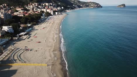 view of the mediterranean shore, large sandy beach, town, mountains