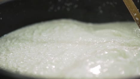 fermented milk mixed in bucket with a wooden ladle