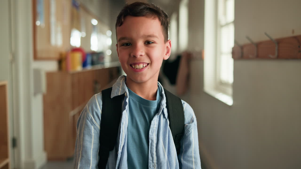 Smiling boy with a backpack in a school hallway