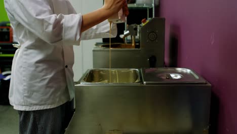 worker pouring white melting chocolate in container